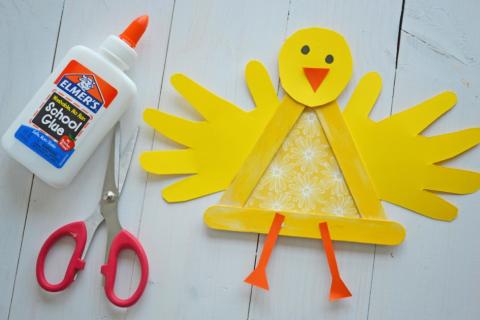 yellow chick made of yellow paper and popsicle sticks with glue and scissors