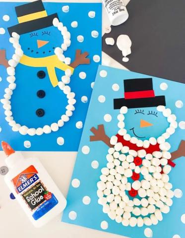 blue cardstock background with white mini marshmallows in the shape of a snowman and construction paper for arms and clothes